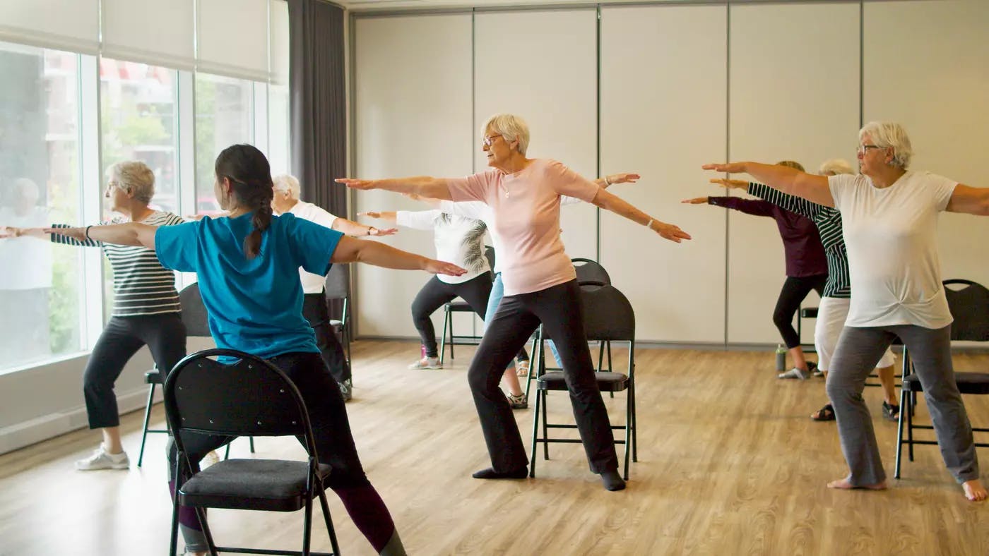 A group of seniors are taking Chair Yoga class at Chartwell residence / Un groupe de personnes âgées suit un cours de yoga sur chaise à la résidence Chartwell