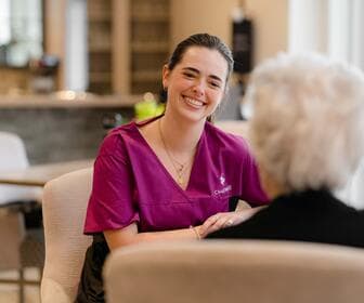 Chartwell staff is smiling big while having a conversation with a residence / Le personnel de Chartwell affiche un grand sourire tout en discutant avec un résident