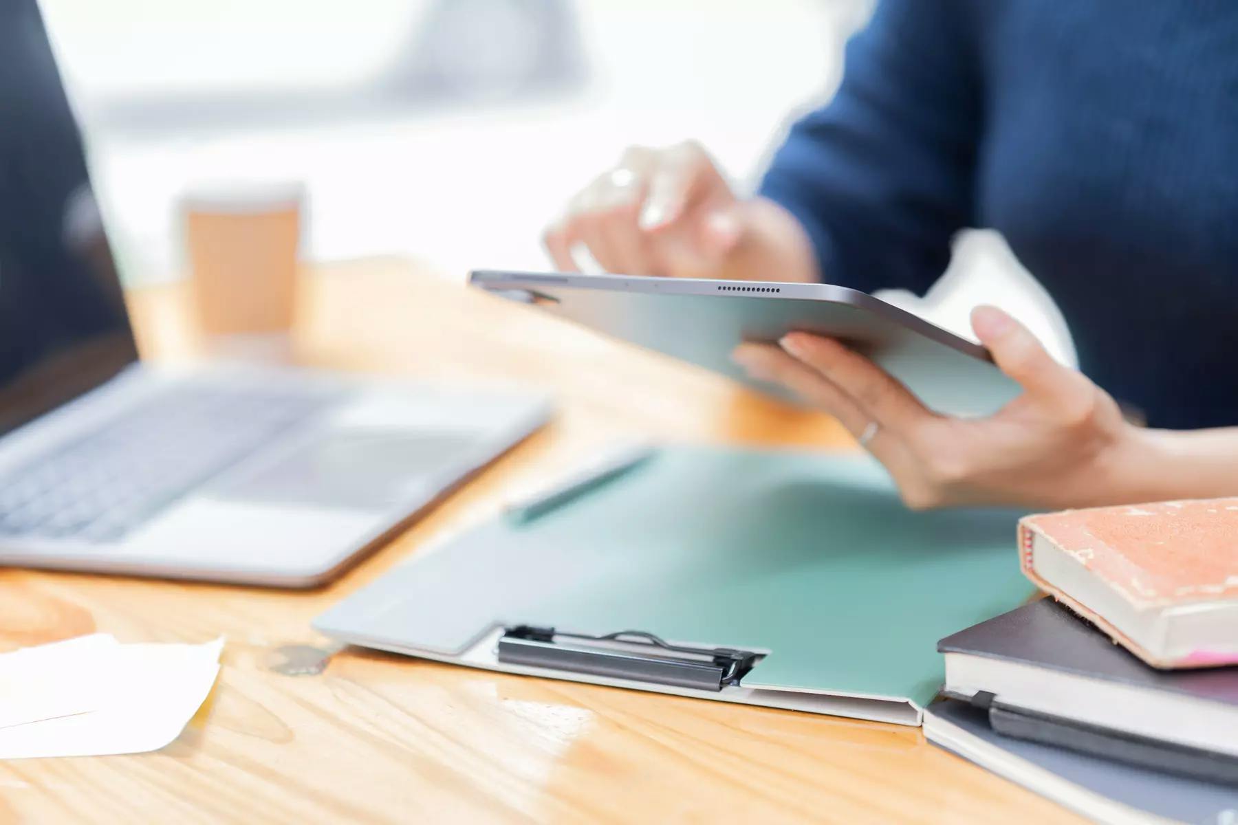 A person using a tablet device on her desk / Une personne utilisant une tablette sur son bureau